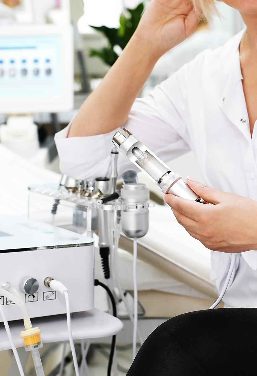 A medical worker in a white laboratory coat holds mesotherapy equipment in a clinical setting.